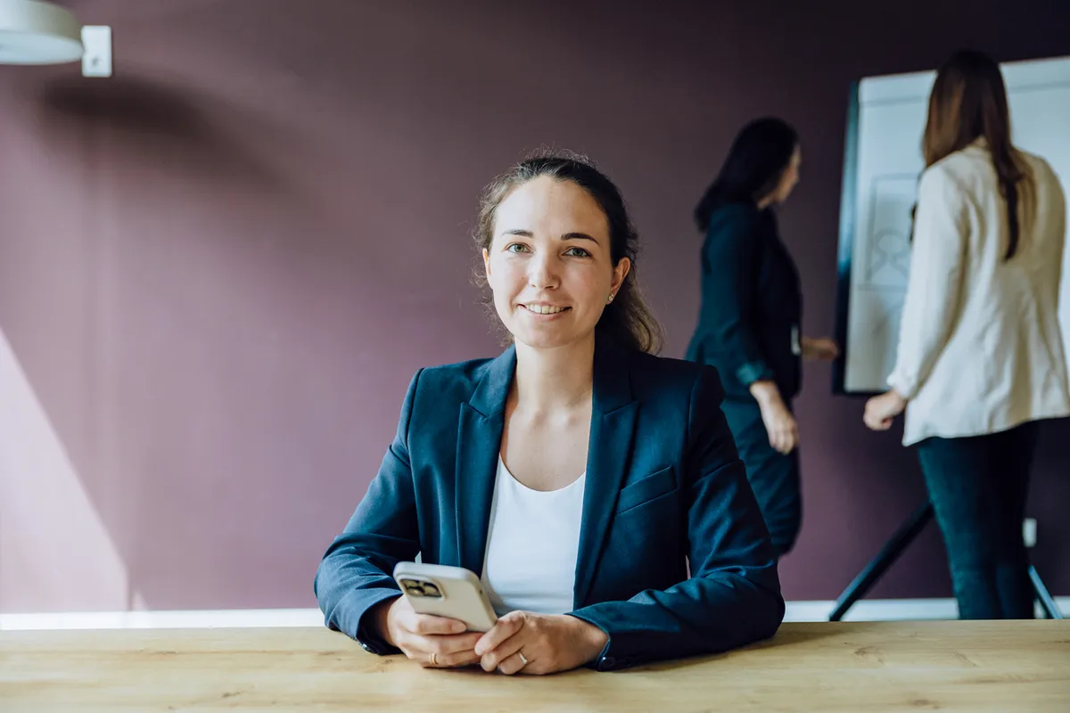 Woman smiling while holding a smartphone - Book initial consultation